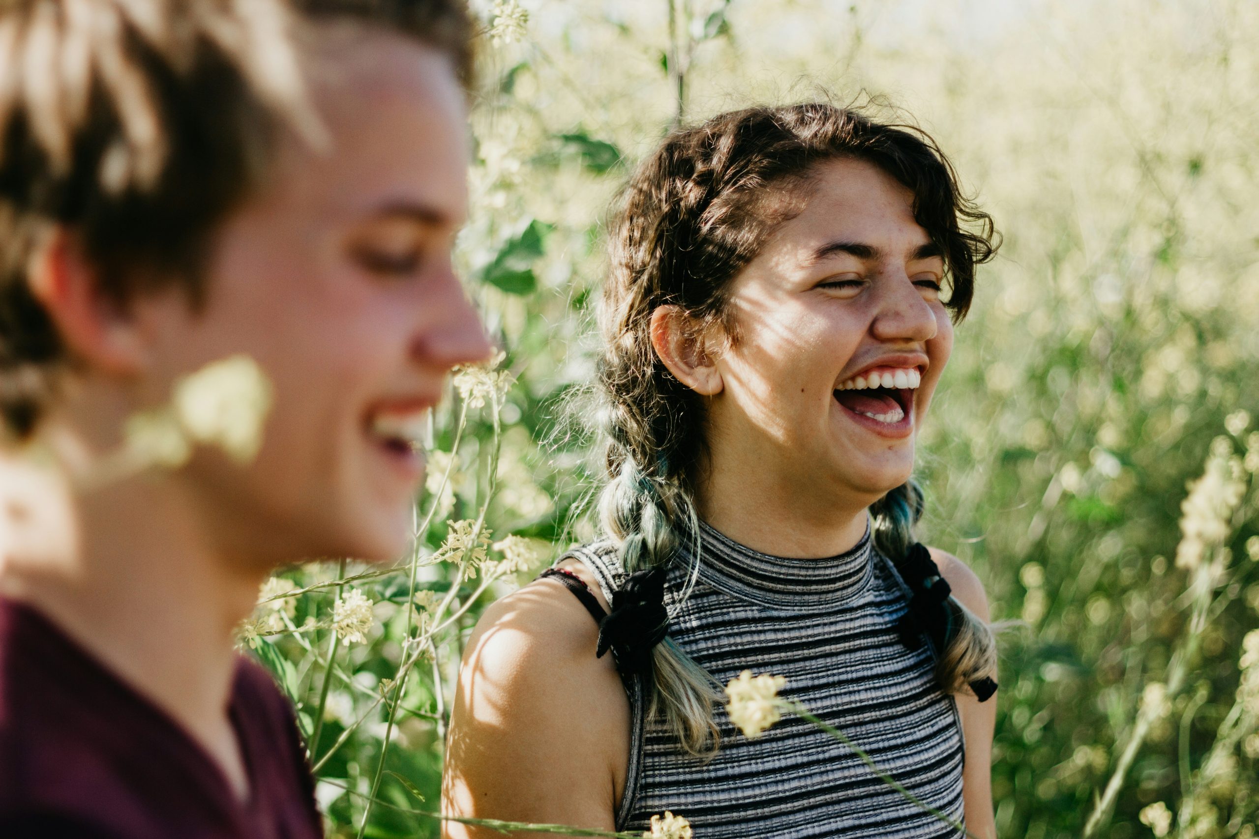 A girl and a boy laughing and enjoying a picnic in the community garden, surrounded by greenery